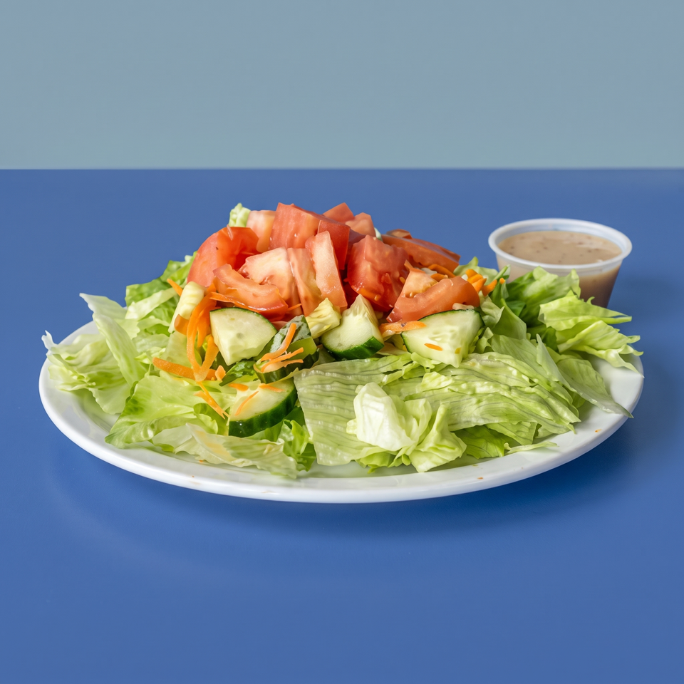Fresh garden salad with lettuce, tomatoes, cucumbers, shredded carrots, and creamy dressing on a white plate.